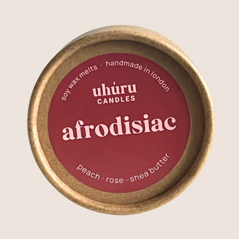 Uhuru Candles Afrodisiac soy wax melt container with red lid on a beige background