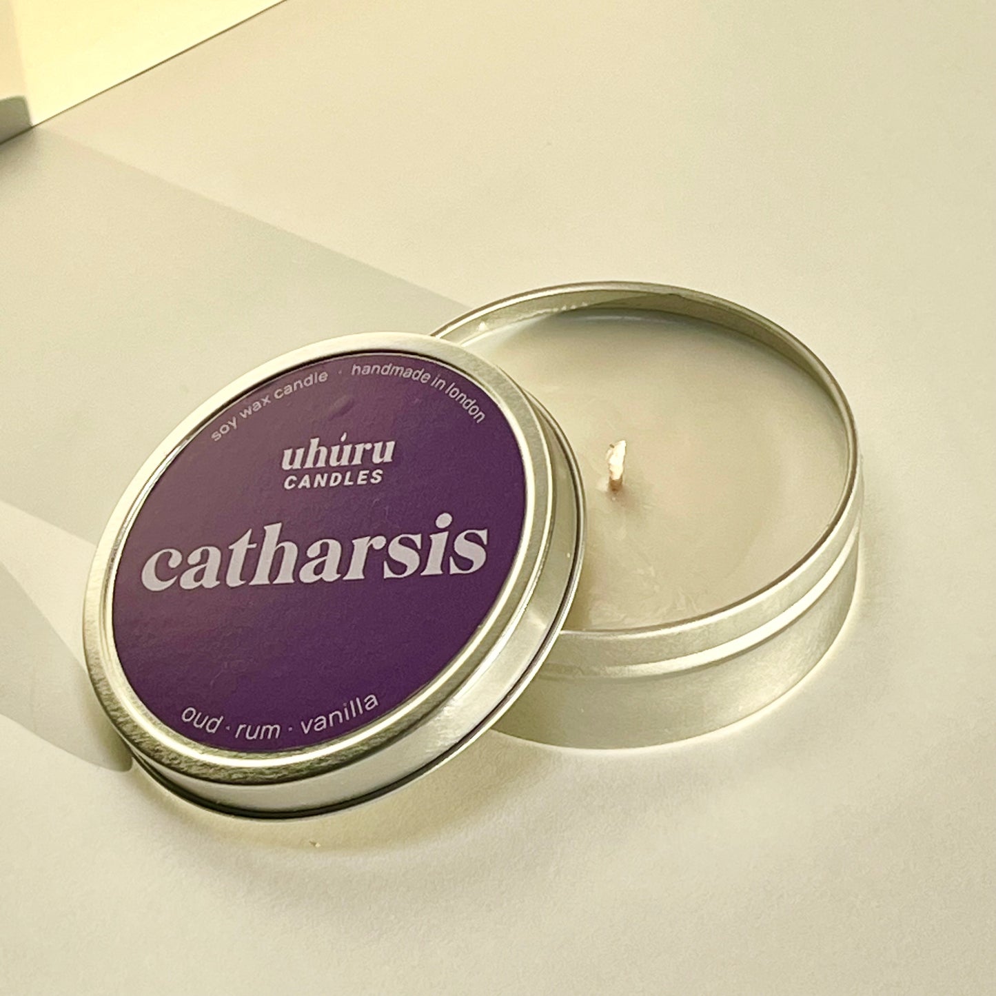 Catharsis by Uhuru Candles - oud, rum and vanilla scented soy wax candle in metal tin with lid off. Tin net weight 70g.