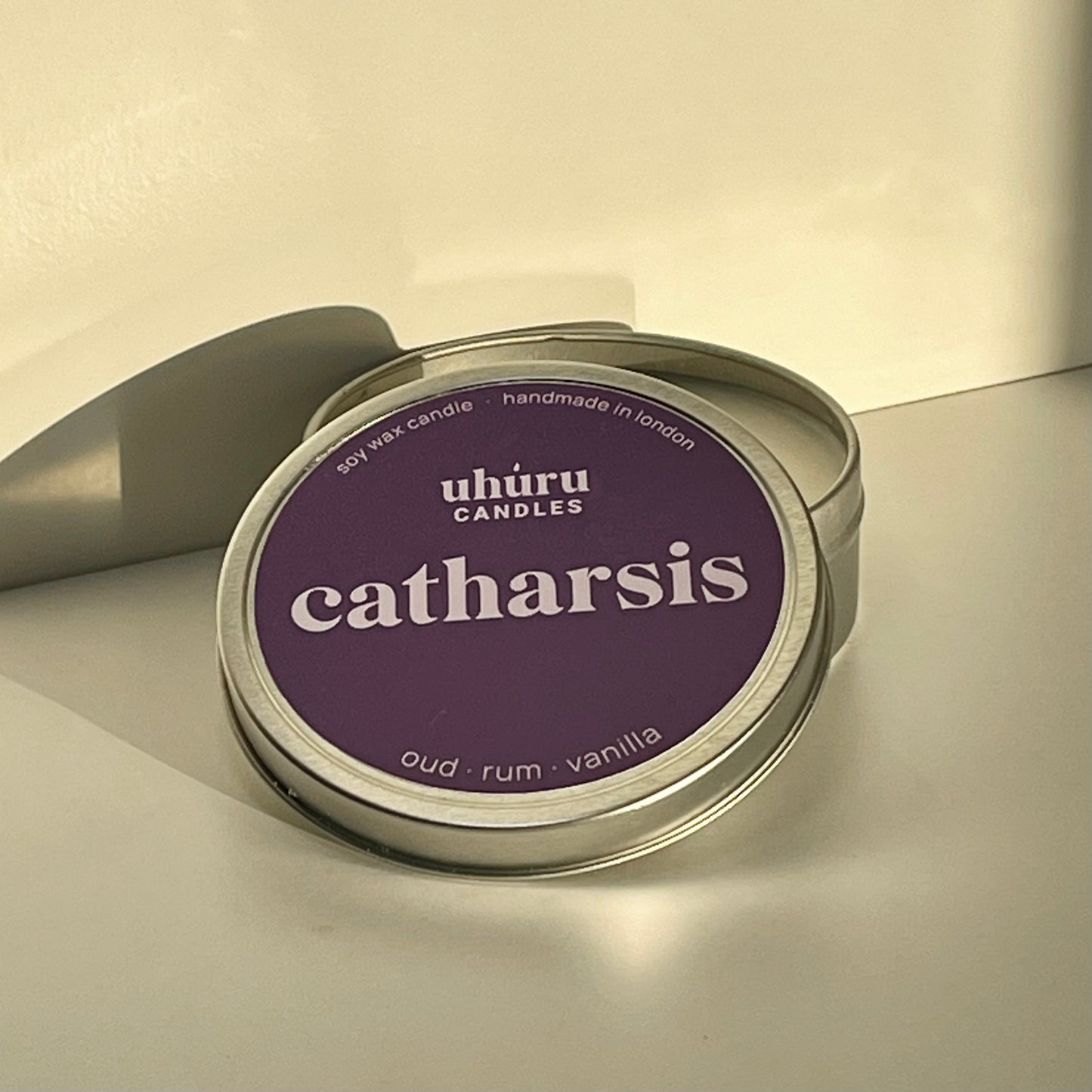 Catharsis by Uhuru Candles - oud, rum and vanilla scented soy wax candle in metal tin with open lid. Tin net weight 70g.