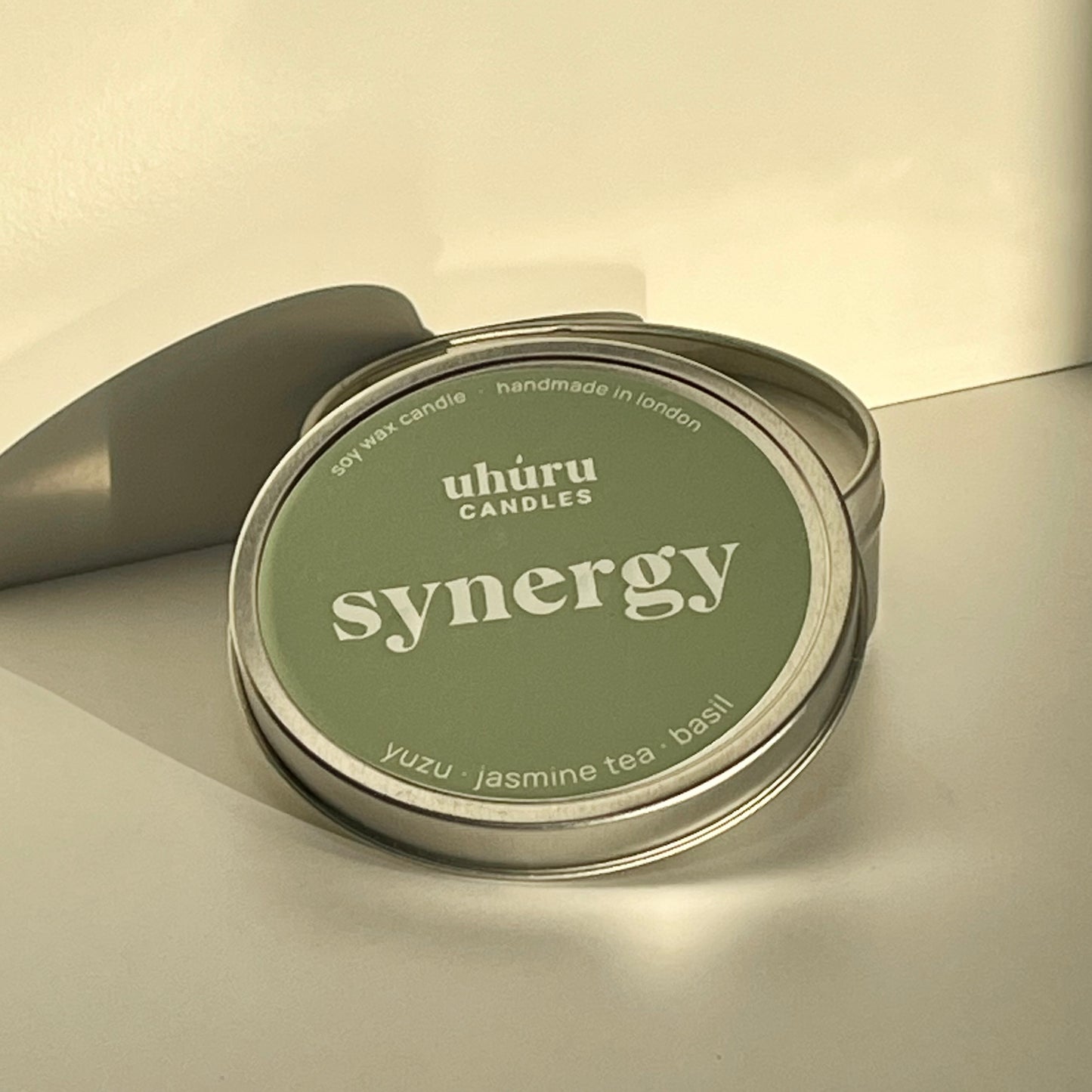 Synergy by Uhuru Candles - yuzu, jasmine tea and basil scented soy wax candle in metal tin container with open lid. Tin net weight 70g.