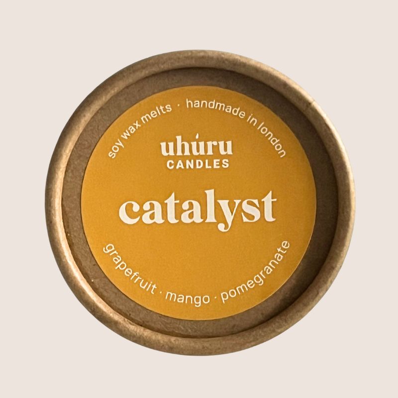 Uhuru Candles Catalyst soy wax melt container with a yellow lid on a beige background