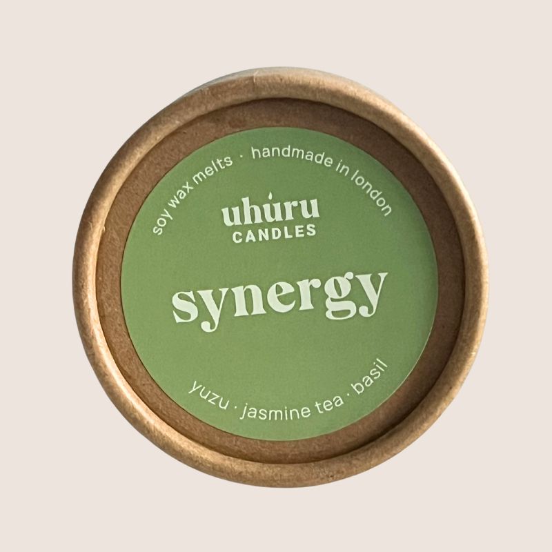 Uhuru Candles Synergy soy wax melt container with green lid on a beige background