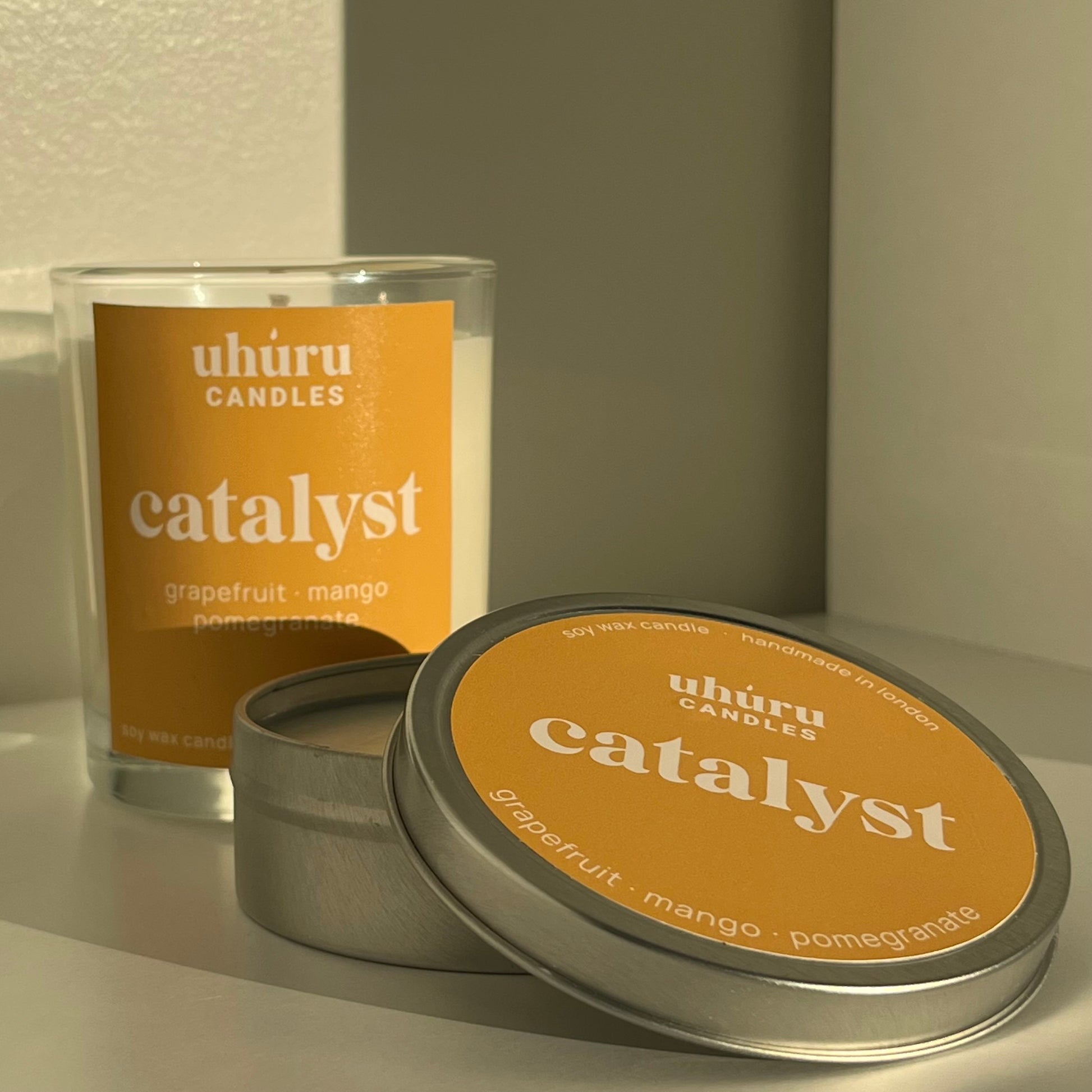 Catalyst by Uhuru Candles - grapefruit, mango and pomegranate scented soy wax candle in glass jar container and metal tin. Jar net weight 150g. Tin net weight 70g.