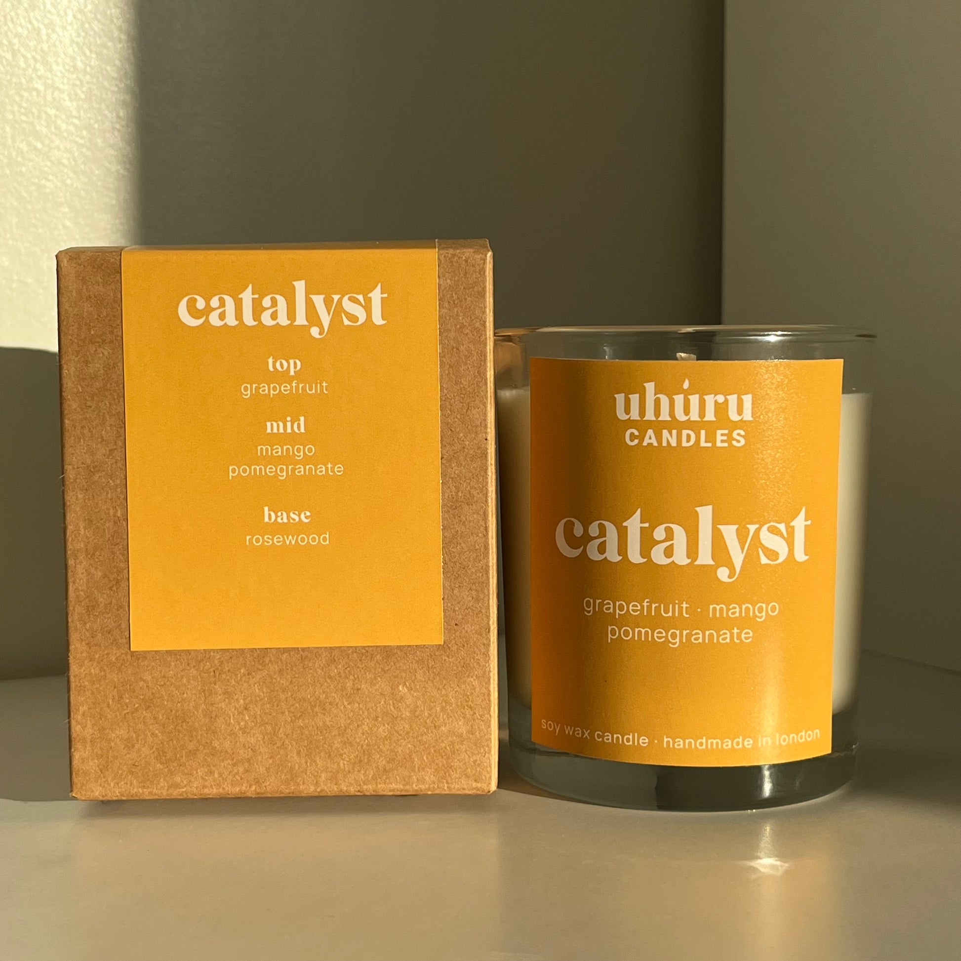 Catalyst by Uhuru Candles with matching recyclable and sustainable cardboard box - grapefruit, mango and pomegranate scented soy wax candle in glass jar container. Net weight 150g.